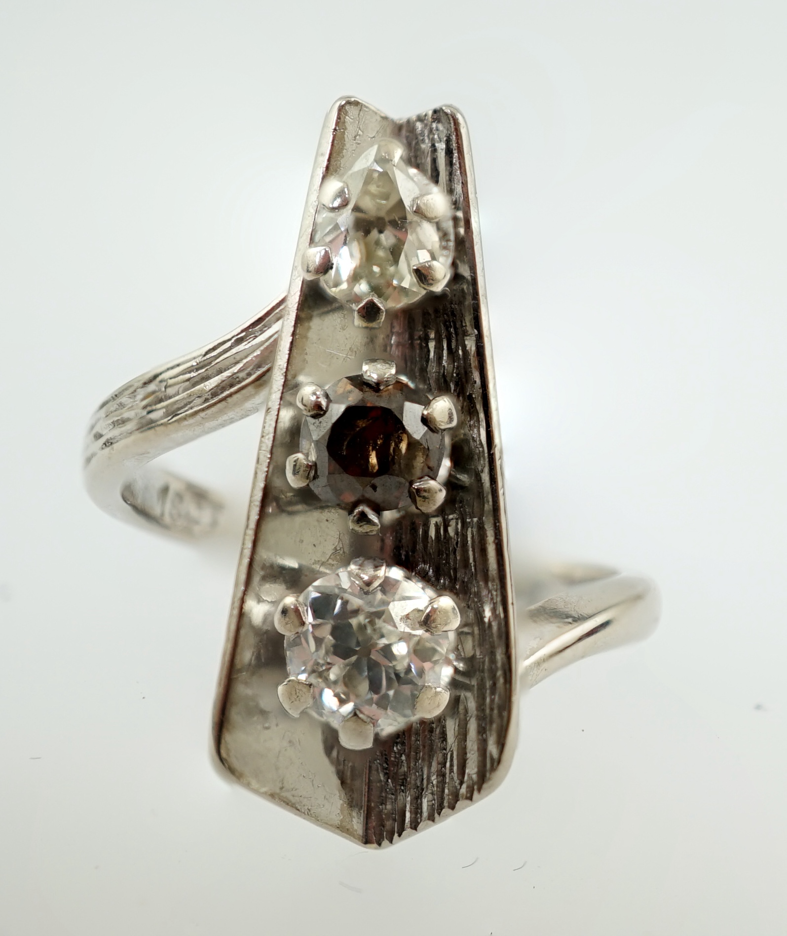 A 1970's 18ct white gold and graduated three stone diamond modernist ring